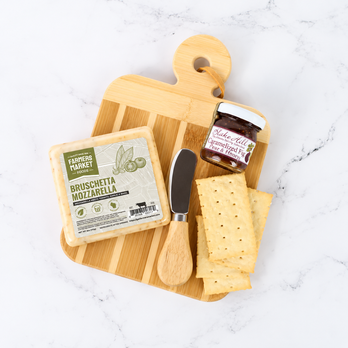 Wooden cutting board with cheese, a knife, and a jar of jam on a white surface