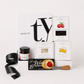 A curated gift box set from Jessica & Co. arranged on a white marble surface, featuring a white 'Thank You' card, a jar of preserves, water crackers, cranberry sauce, cheese spread, a small knife, and a black textured insert inside a gift box.